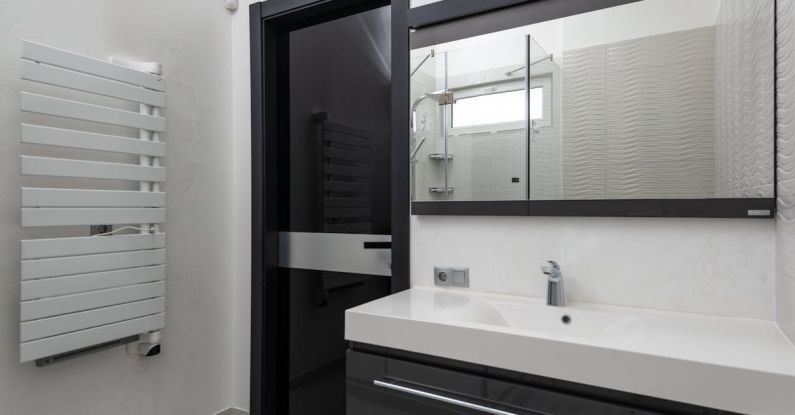 Heated Floors - Creative design of bathroom with door between heated towel rail and washstand under rectangular mirror in light house
