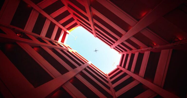 Focal Point - Low-angle Photography of Building Showing Airplane on Skies
