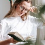 Water Heating - Attentive woman in eyewear reading notebook at home