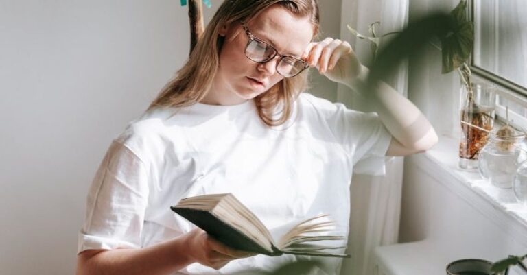 Water Heating - Attentive woman in eyewear reading notebook at home