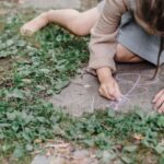 Chalk Paint - High angle of crop unrecognizable barefooted child painting on ground with colorful chalks while playing in green garden