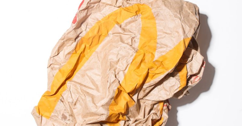 Garbage Disposal - Top view of crumpled empty craft paper bag of fast food restaurant placed on white background illustrating recycle garbage concept